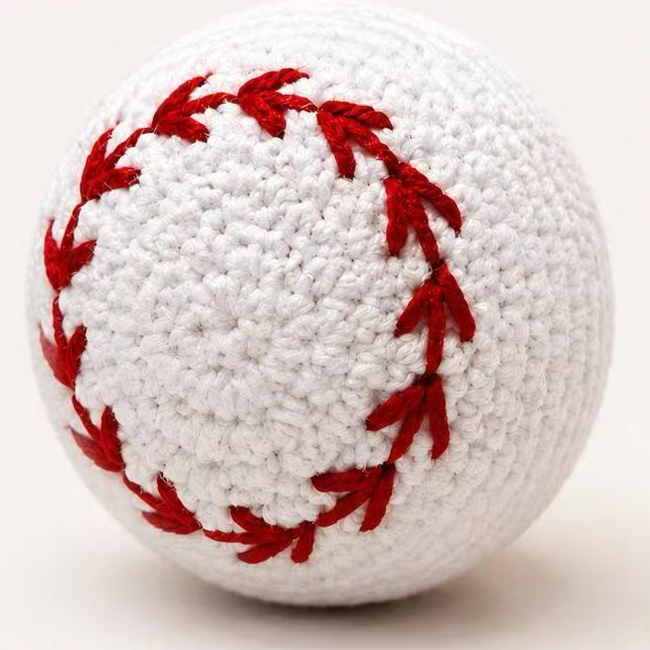White crochet-style baseball dog toy with red stitching, approximately 8 cm in diameter.