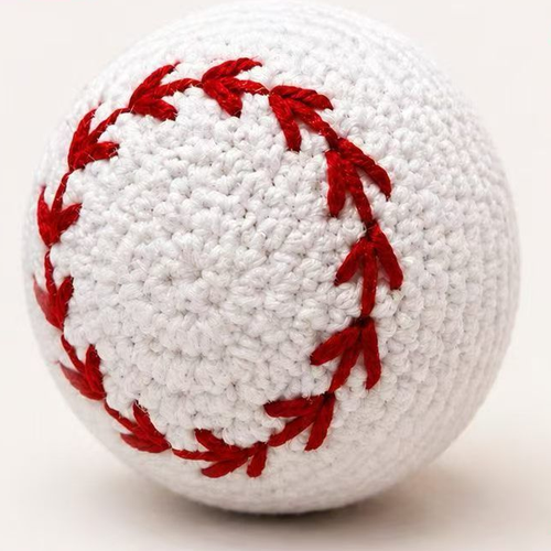 White crochet-style baseball dog toy with red stitching, approximately 8 cm in diameter.